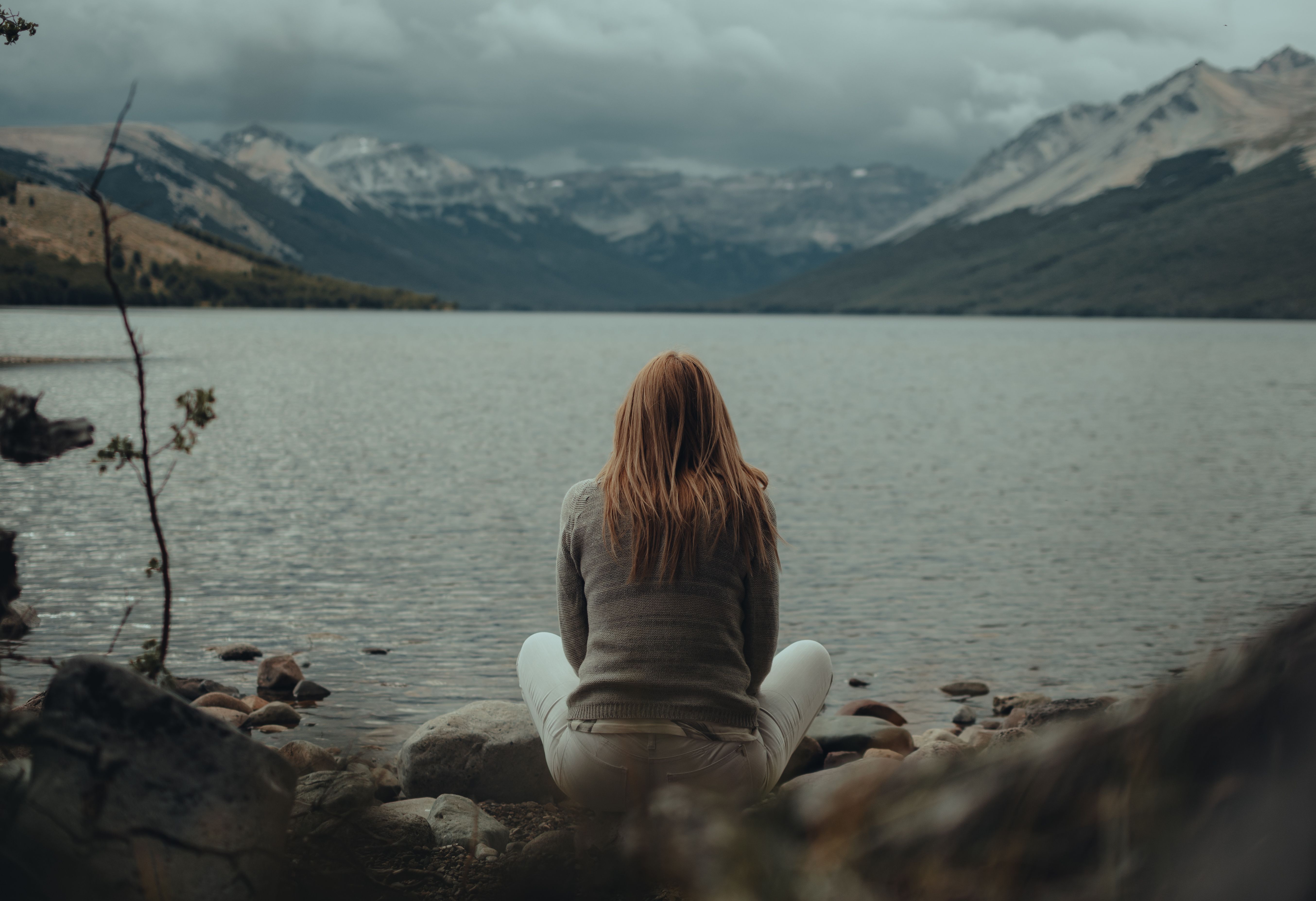 A woman sitting quietly beside a mountain lake