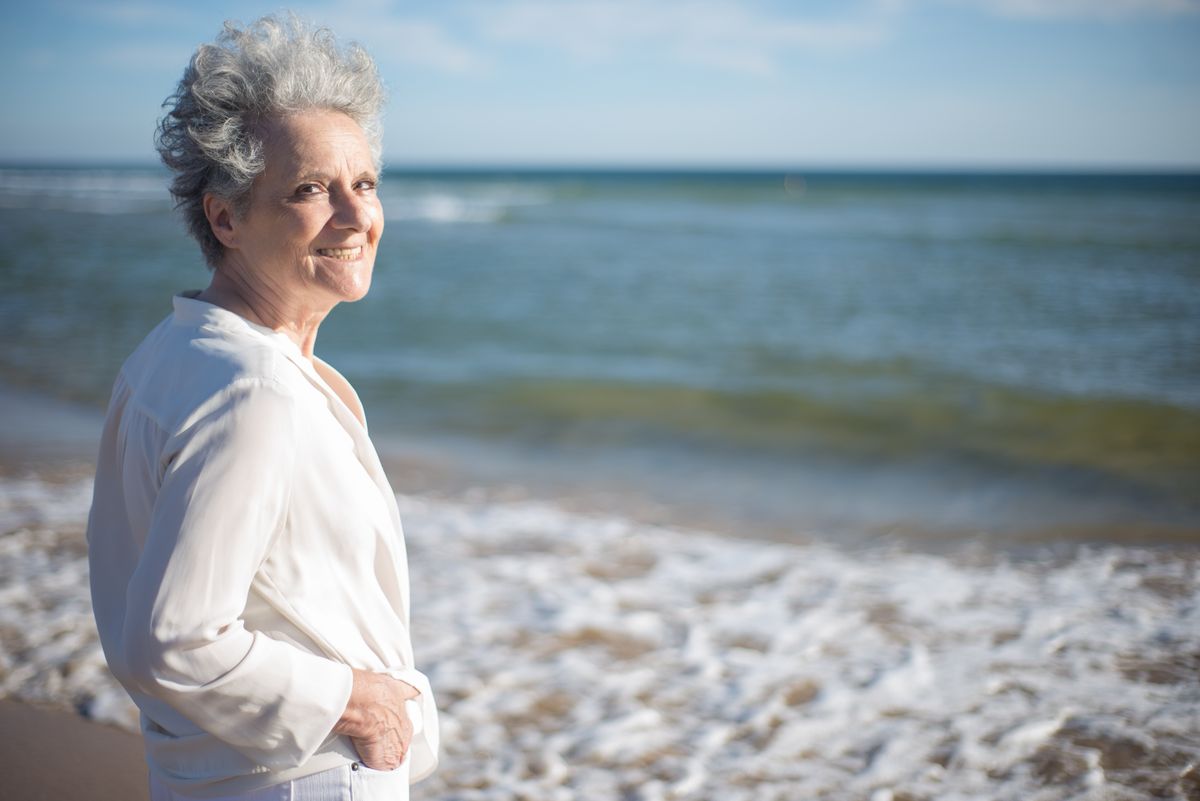 A smiling senior woman with gray hair by the sea
