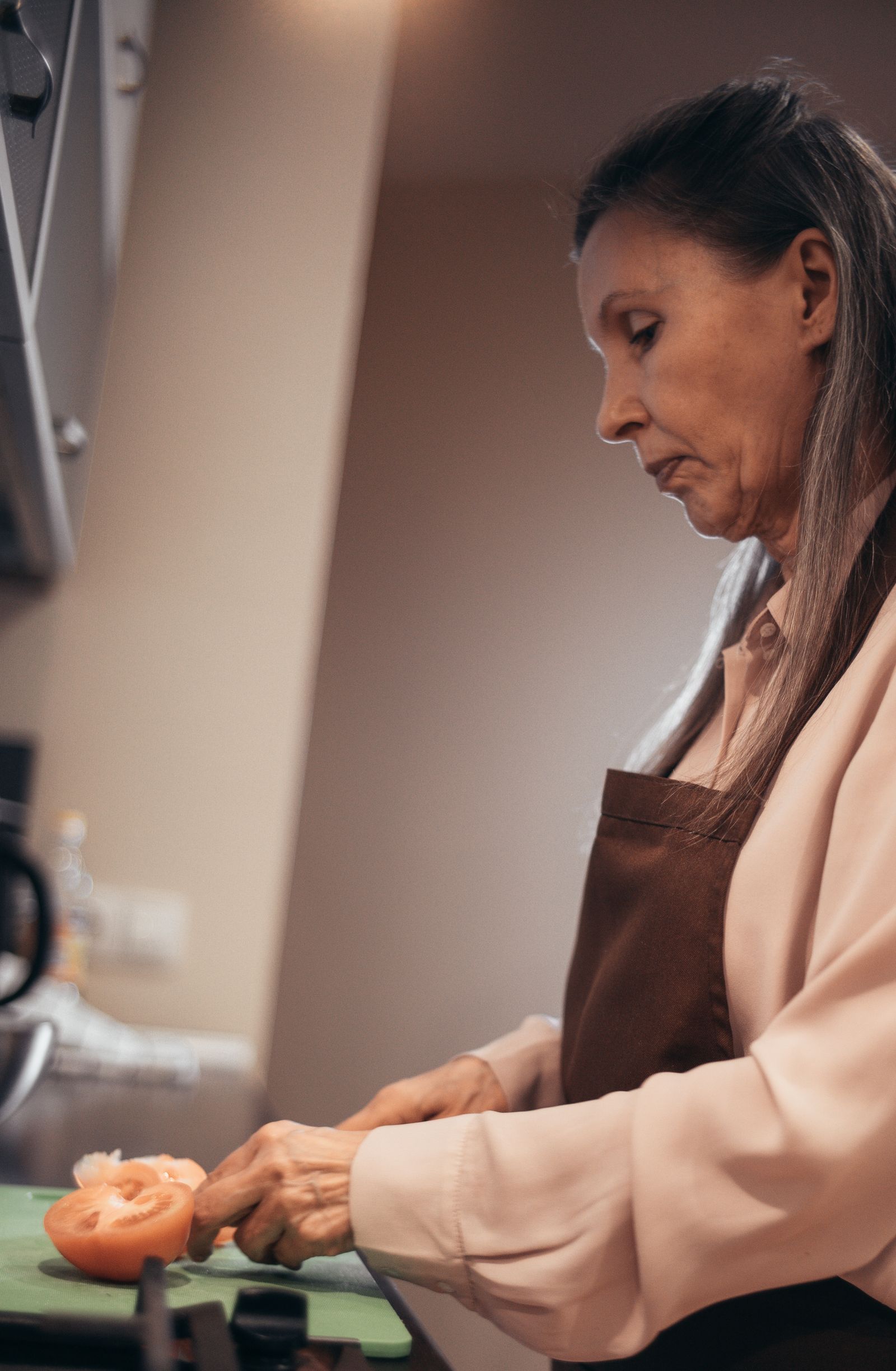 An older woman chopping fresh vegetables in her kitchen