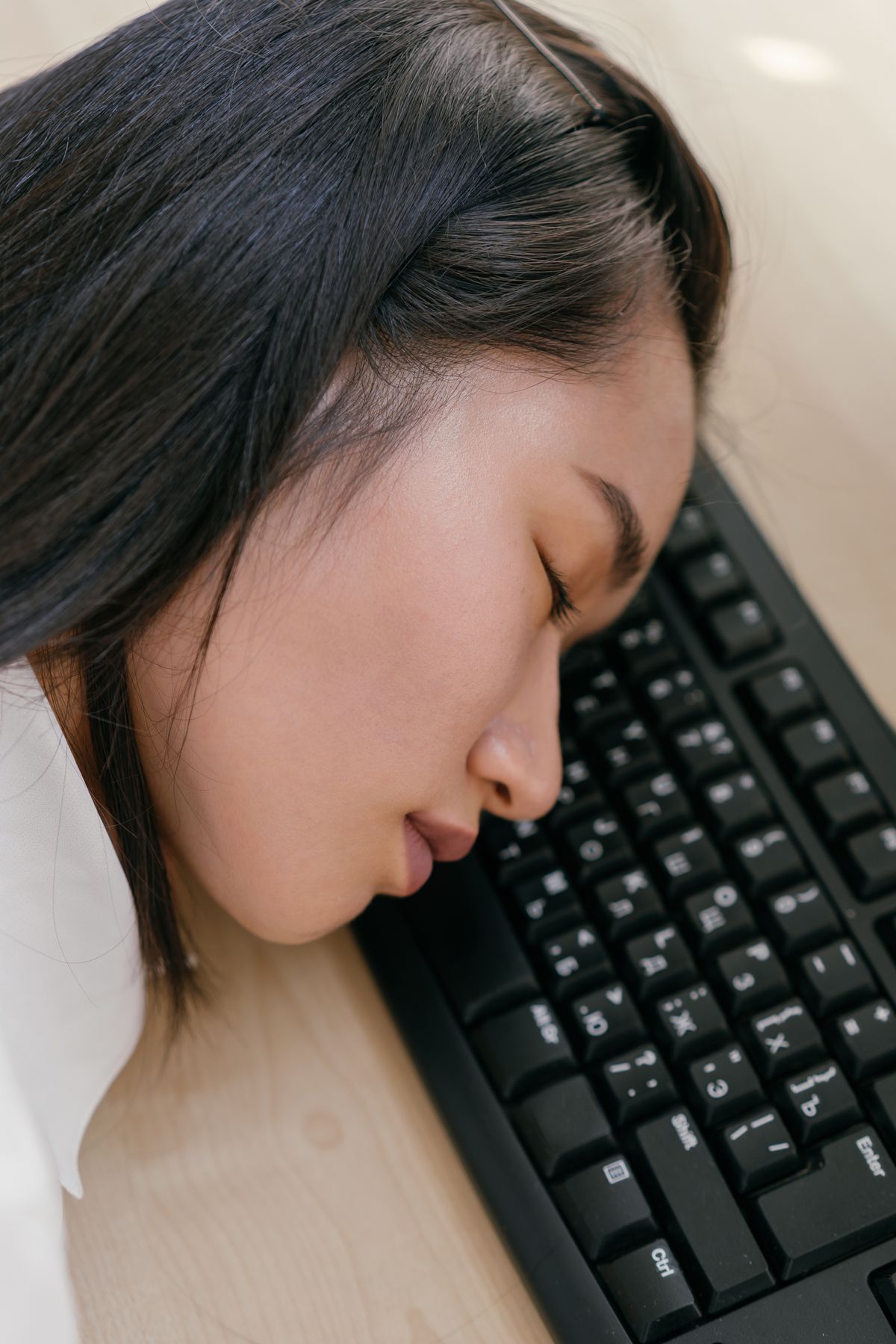 A tired woman resting her head on a keyboard