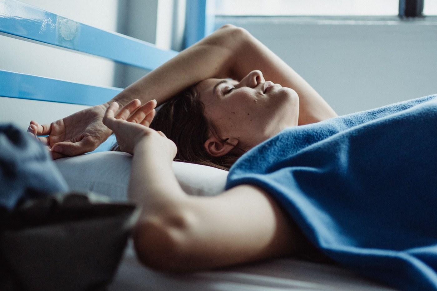 A woman sleeping under a blanket in a naturally lit bedroom